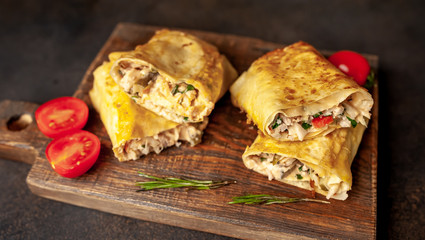 Mexican burrito wraps with chicken and vegetables on a cutting board, on a background of concrete, mexican shawarma