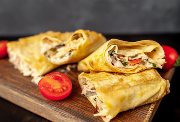Mexican burrito wraps with chicken and vegetables on a cutting board, on a background of concrete, mexican shawarma