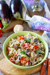 Vegetarian menu, healthy diet food. Rice with vegetables, mushrooms and eggplants in a bowl on a wooden table.