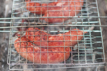 Sausages on the grill are grilled on the coals in the open air.