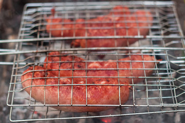 Sausages on the grill are grilled on the coals in the open air.