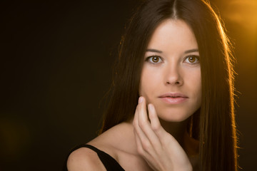 Portrait of beautiful young woman on black background and yellow lights