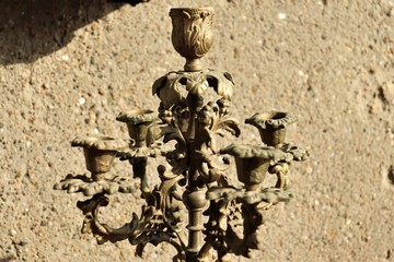 Gold dusty candlestick against a stone surface.