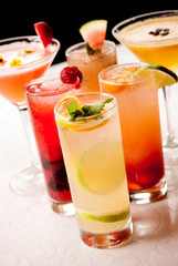 Colorful cocktail drinks with garnishes on white table