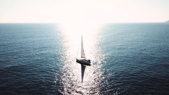 Turkey, Mediterranean sea - 27.10.2019: Silhouette of a yacht under sail opposite the reflection of the sun from the water
