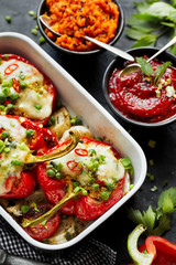 Baked  bell peppers stuffed with groats,  vegetables and mozzarella cheese in a baking dish, close up