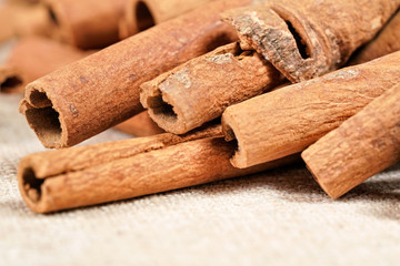 Closeup macro photo - Heap of cinnamon bark sticks on linen tablecloth.