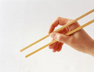 Hölzerne Asiatische Stäbchen in einer Hand isoliert auf weißen Hintergrund