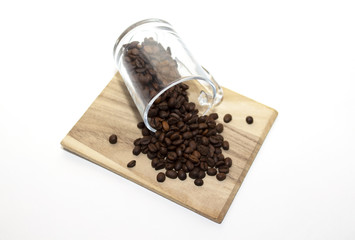 Scattered coffee beans on the woodaen plank. Copy space. Place for text. White background. 