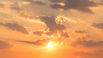 Beautiful incredible orange sunset, sunrise with the rays of the bright warming sun with large air cirrus clouds and birds flying in the distance. Summer peaceful landscape, the awakening of nature