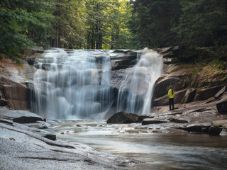 Obraz premium woman standing in front of waterfall in forest