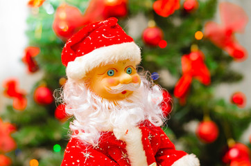 Toy Santa Claus, on the background of the New Year tree, and on the background of the New Year star on the Christmas tree. Toy Santa in close-up. Christmas decoration. Celebration.