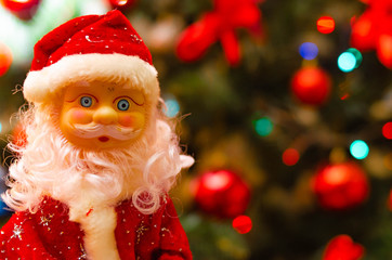 Toy Santa Claus, on the background of the New Year tree, and on the background of the New Year star on the Christmas tree. Toy Santa in close-up. Christmas decoration. Celebration.