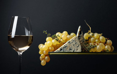 Glass of white wine with snacks. Grapes with blue cheese and thyme.