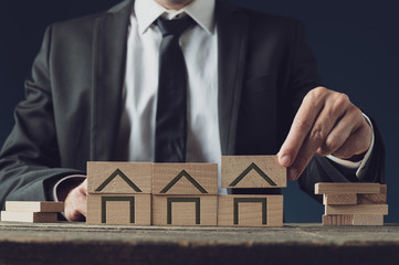 Realtor building houses of wooden blocks