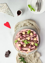 No bake raspberry cheesecake (cream mousse dessert) decorated with chocolate glaze, raspberries, heart shape cookies and mint. Valentine’s day concept. Selective focus.