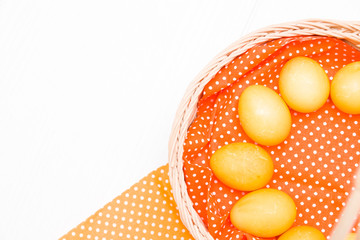 yellow easter eggs in a basket on an orange polka dot fabric, copy space, white background, top view