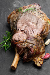 Whole roast lamb leg on black stone background © lena_zajchikova