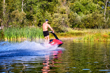 Young man riding water scooter at sea lake river on summer day.