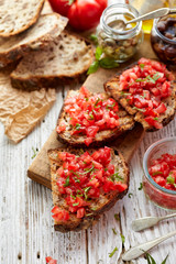 Obraz na płótnie Canvas Bruschetta with tomatoes, fresh basil and olive oil on a wooden board, close up, top view. Traditional mediterranean cuisine