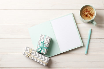 Flat lay composition with notebooks, coffee and gift box on wooden background