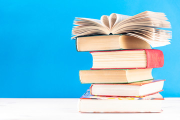 Heart shaped book pages on a stack of old hardback books with text dlch space. Back to school. Education