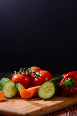 Composition with raw vegetables. Composition with variety of fresh organic vegetables. Side view, vertical, reamer with cucumber and tomatoes