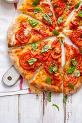 Homemade vegetarian  pizza with addition of tomatoes, mozzarella cheese and basil on a white wooden board   ,top view. Traditional pizza margherita