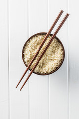 Uncooked indian long rice in bowl and chopsticks.