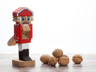 Nutcracker with inshell walnuts on wooden surface