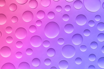 Top view of water drops on the glass close-up. Pink and blue gradient background