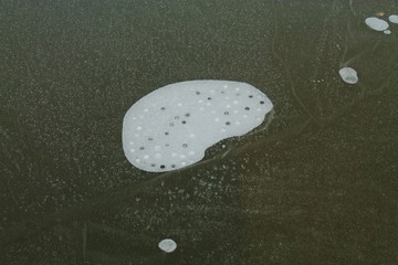 The air bubble froze into the ice. Frost froze the air bubble. There are air cavities in the ice