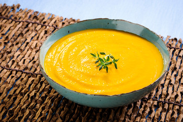 A bowl of vegetable soup, on a wooden table mat