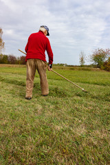 Naklejka na ściany i meble old senior farmer raking lawn