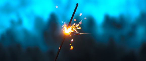 Sparklers for Christmas and New Year close-up in the form of a banner and on a blue background