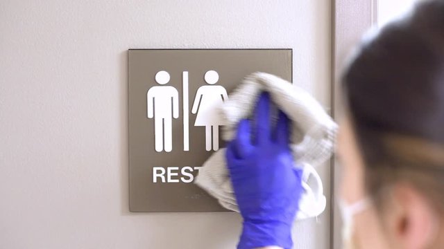 Slider movement of janitor woman cleaning male female restroom sign on wall in medical office, hospital, doctors office. 