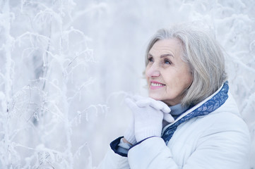 Portrait of happy beautiful senior woman posing in snowy winter park
