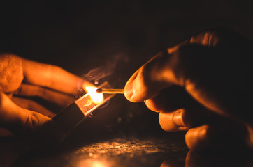 Magic lit match with cool colored smoke in the hands, warm color