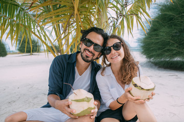 Happy couple of lovers with cocktails on a tropical beach.