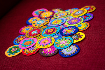 Small round embroidery, full of colors, shown on a red background