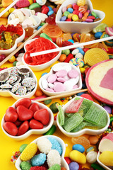 candies with jelly and sugar. colorful array of different childs sweets and treats on yellow background