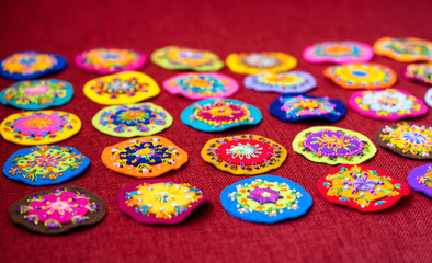 Fototapeta na wymiar Small round embroidery, full of colors, shown on a red background