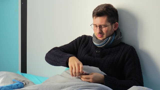 A young man suffering fever,  Lying in Bed in taking pills - Medium Shot