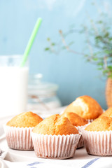 Freshly baked homemade muffins in white paper muffin cups and a glass of milk on the table. Tasty sweet breakfast, homemade cakes.