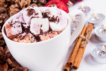 Cup of hot chocolate with marshmallows, and some cinnamon sticks, cones, christmas balls and candles	