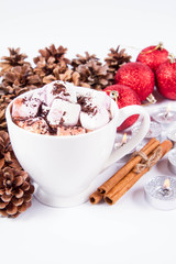 Cup of hot chocolate with marshmallows, and some cinnamon sticks, cones, christmas balls and candles	