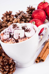 Cup of hot chocolate with marshmallows, and some cinnamon sticks, cones, christmas balls and candles	