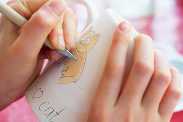 Child paints a mug in a pottery workshop.