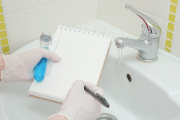 Result of tap water analysis quality control concept. Hand with a flask, blank notepad with copy...