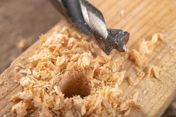 Drilling with a drill bit into wood. Small carpentry work in a carpentry workshop.